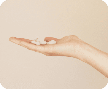 A hand holding several white pills