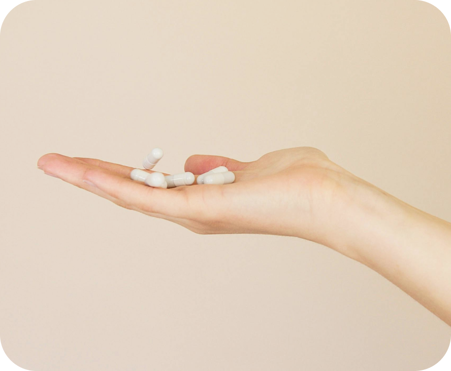 A hand holding several white pills