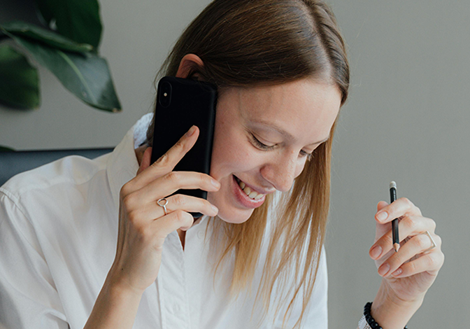 A woman smiling while she chats on the phone.