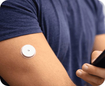 A closeup of a person's arm with a white medical device patch on their bicep.