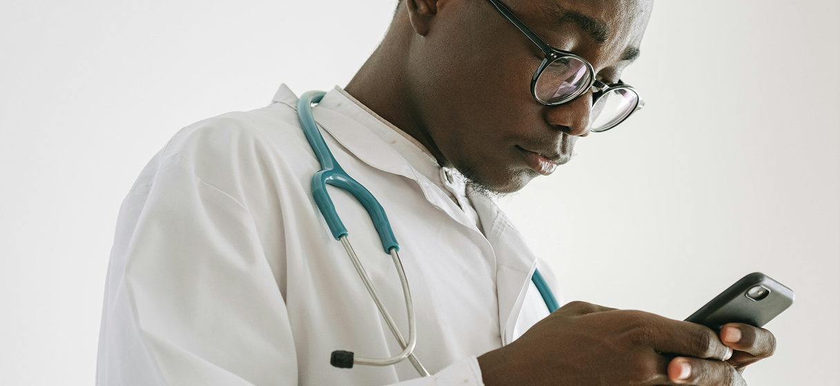 A doctor reading a text message on their phone. The message looks to be important.