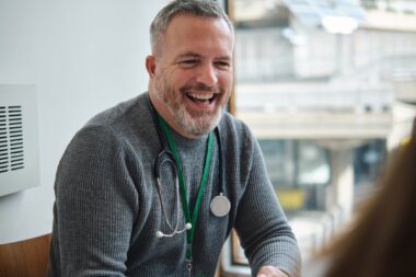 Male Doctor With Patients in Exam Room